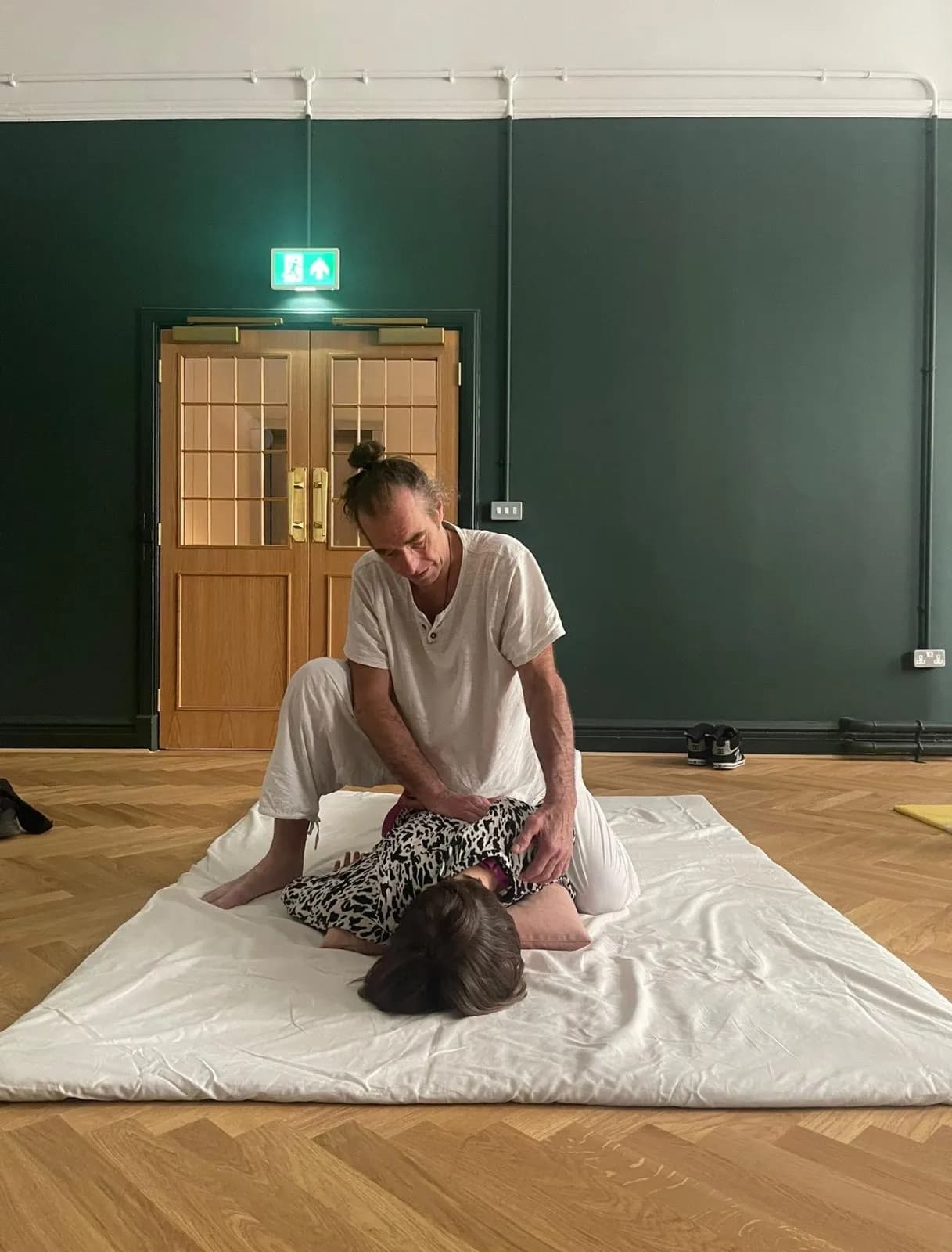 Shiatsu massage being performed on a floor mat