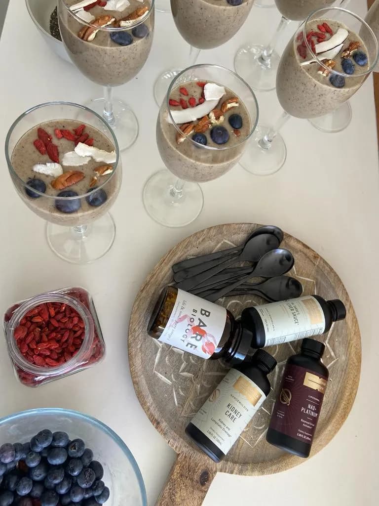 Chia and berry breakfast pots beside liver, kidney and NAD+ support supplements on a wooden board