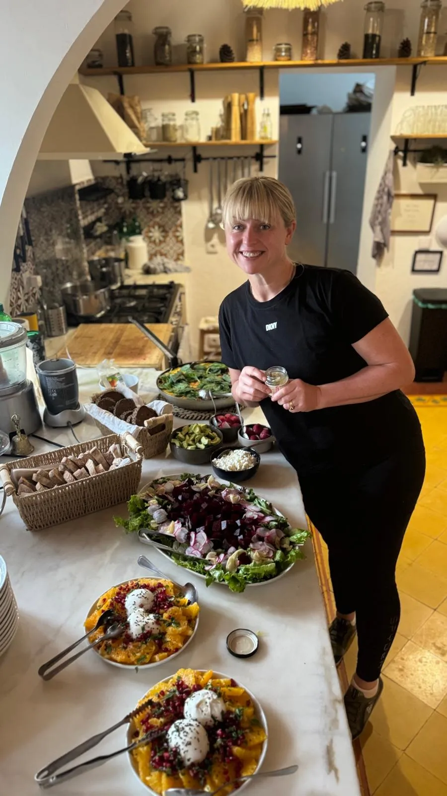 Niki Charnock beside a table laid with fresh salads, fruit and nourishing dishes